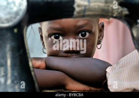 Petite fille se cacher derrière une vieille machine à coudre mécanique, camp pour les victimes de tremblement de terre de janvier 2010 Banque D'Images