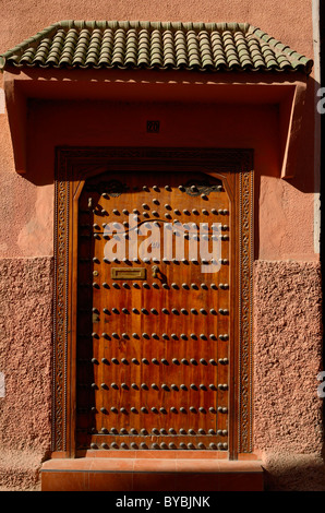 Porte en bois de l'ocre rouge et le mur d'une maison dans le souk medina de Marrakech Maroc marché Banque D'Images