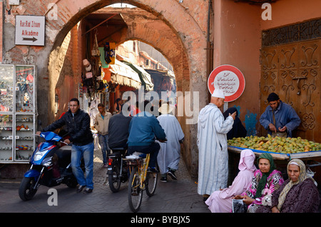 De la circulation des piétons et des vélos à la place Djemaa el Fna de boutiques dans les ruelles des souks de médina de Marrakech Maroc avec de vieilles femmes assis Banque D'Images