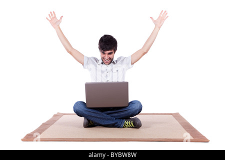 Jeune homme la navigation sur internet dans son ordinateur portable se trouve sur le tapis (isolé sur blanc) Banque D'Images