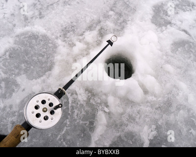 Gros plan sur la pêche sur glace canne tenue sur un trou dans la glace. Banque D'Images