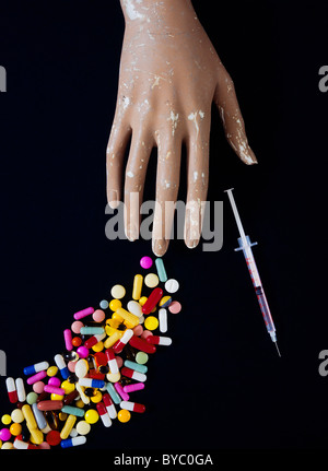 La main factice avec capsules comprimés comprimés pharmaceutiques & aiguille hypodermique Banque D'Images