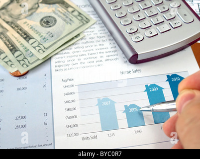 Homme de main avec un crayon sur le tableau d'investissement avec la calculatrice et dollars Banque D'Images