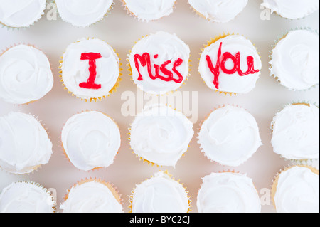 Rangées de cupcakes avec lettres rouges "I Miss You" écrit sur haut de glaçage blanc Banque D'Images