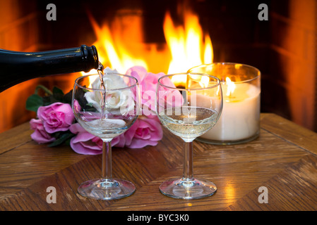 Le vin blanc est versé dans l'un des deux verres d'une cheminée dans l'arrière-plan. Banque D'Images