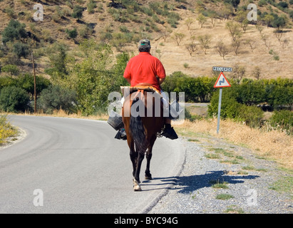 Vue arrière de l'homme à cheval passant un panneau routier dans les virages en Andalousie Espagne. Banque D'Images