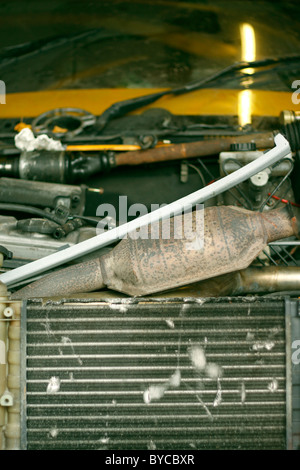 Le radiateur d'une voiture à l'intérieur d'un garage, et le catalyseur de l'échappement parmi un tas d'outils. Banque D'Images