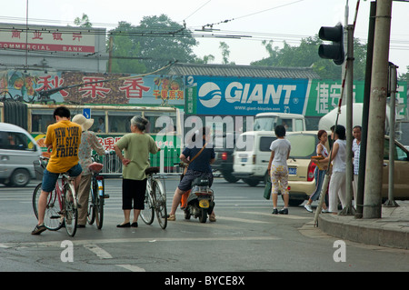 Les gens sur les bicyclettes s'est arrêté à un feu rouge, le quartier de Hutong, Beijing, Chine. Banque D'Images