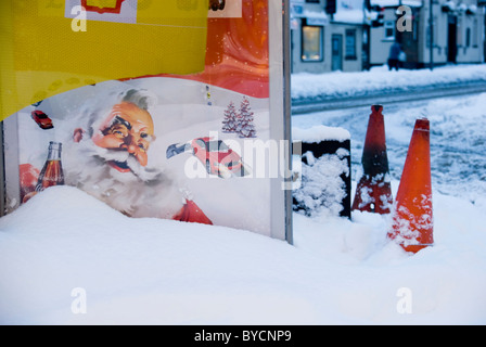 Panneau publicitaire avec un Père Noël enterrés dans la neige sur la rue de la ville au crépuscule, Sheffield, Angleterre Banque D'Images