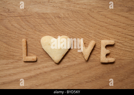 L'amour, mot écrit avec des biscuits, avec une forme de coeur O Banque D'Images