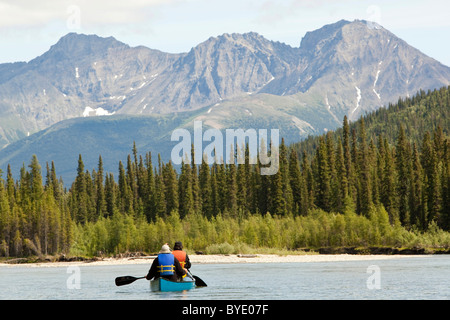 Deux hommes dans un canot, kayak, canoë kayac Upper Liard River, monts Pelly derrière, Territoire du Yukon, Canada Banque D'Images
