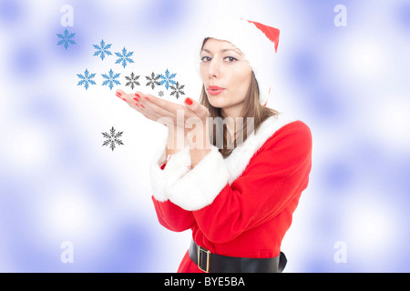 Femme en costume père noël flocons de soufflage Banque D'Images