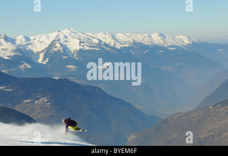 Un skieur effectue une main glisser sur une crête dans la station de ski de Courchevel en France. Banque D'Images