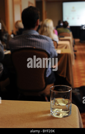 Vue depuis l'arrière d'une salle de conférence où un groupe de gens d'affaires méconnaissable écoute attentivement. Banque D'Images
