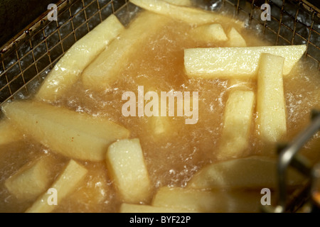 La friture fait maison fraîchement coupé à partir de copeaux de pommes de terre dans une friteuse profonde Banque D'Images