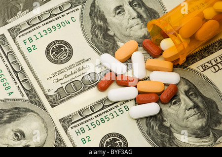 Une variété de pilules et vitamines d'un déversement sur bouteille orange de 100 dollars américains. Banque D'Images