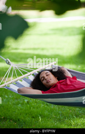 Jeune homme aux cheveux afro en couchage hamac dans park Banque D'Images