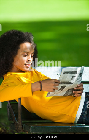 Jeune homme aux cheveux afro journal de lecture sur l'établi Banque D'Images