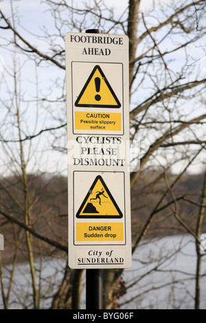 Un panneau d'avertissement sur un sentier public informant d'un pont avant et une chute soudaine, Sunderland, Angleterre, RU Banque D'Images