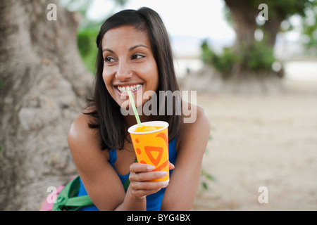 Femme buvant un verre froid de glace par tree Banque D'Images