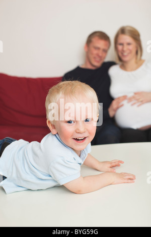 Young couple sitting on sofa, fils couché sur l'avant à l'arrière-plan Banque D'Images