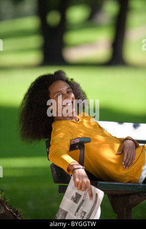 Smiling Young man with afro hair relaxing on bench Banque D'Images