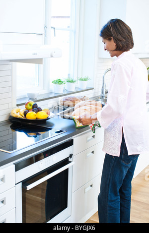 Femme tenant le pain sur le plateau dans la cuisine Banque D'Images