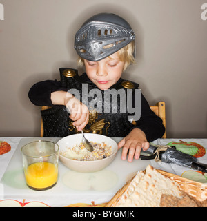 Garçon en armure eating breakfast Banque D'Images