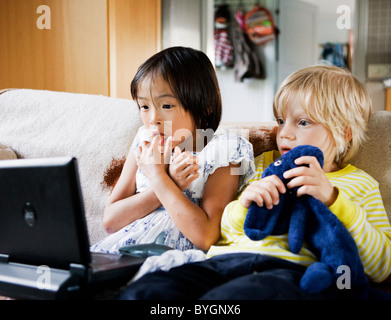 Garçon et fille regarder la télé sur canapé Banque D'Images