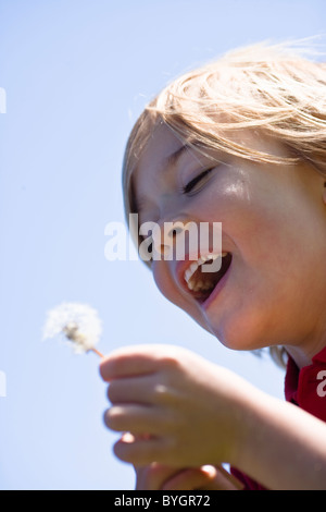 Boy blowing dandelion en plein soleil Banque D'Images