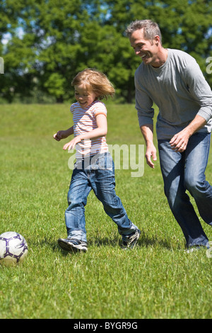 Père et fils à jouer au football en plein soleil Banque D'Images