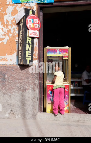 Une jeune fille joue avec une machine de jeu vidéo dans une rue d'Ayacucho Banque D'Images