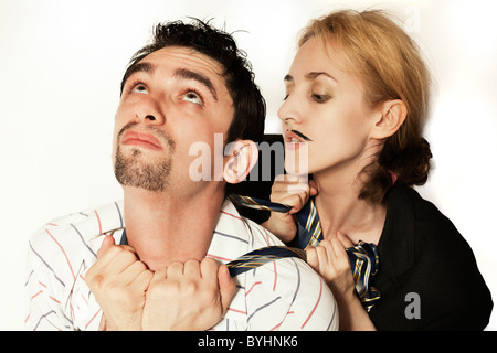 Femme avec une moustache artificielle d'étrangler un jeune homme cravate sur fond blanc Banque D'Images