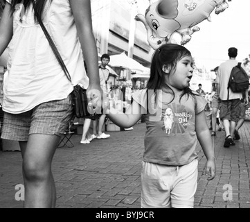 Photographie noir et blanc photographie candide d'une jeune fille thaïe dans une rue Banque D'Images