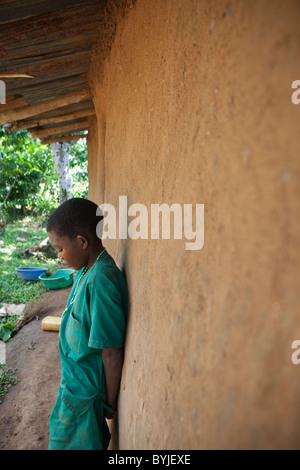 Un jeune enfant est seul à l'extérieur de sa maison dans les régions rurales de Masaka, en Ouganda, en Afrique de l'Est. Banque D'Images