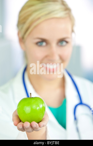 La saine alimentation ou de style concept tiré d'un femme female doctor holding et une pomme verte Banque D'Images