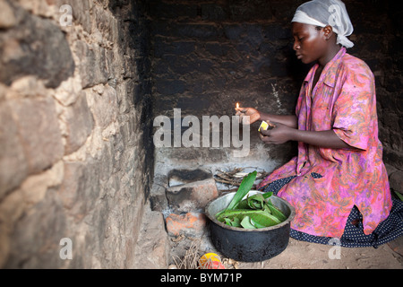 Une femme prépare un repas de bananes pour sa famille dans les régions rurales de Masaka, en Ouganda, en Afrique de l'Est. Banque D'Images