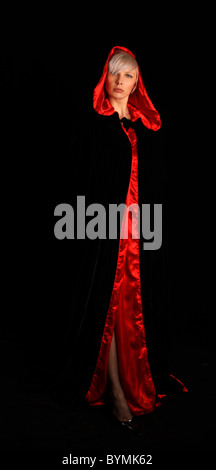 Jeune femme aux cheveux d'argent portant une cape noire bordée de rouge Banque D'Images
