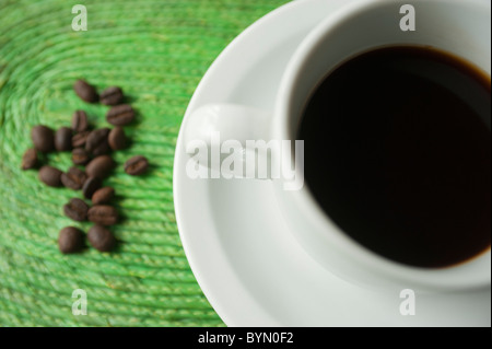 Tasse de café sur le tapis de raphia avec des grains de café fraîchement traitées sur le côté. Honduras, Amérique centrale. Banque D'Images