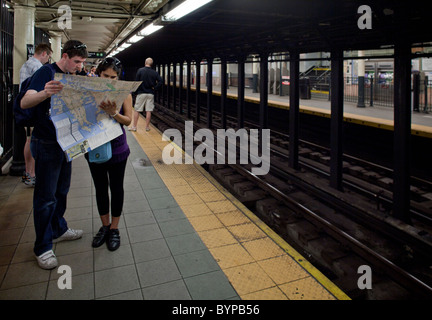 USA, New York, New York City, les jeunes touristes regarder la carte tout en attendant de monter à bord de train de métro à Manhattan Banque D'Images