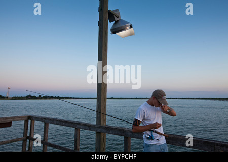 USA, Texas, le lac à l'arrowroot State Park, jeune homme bisous bonne chance pour les poissons pendant la pêche du quai public de soir d'été Banque D'Images