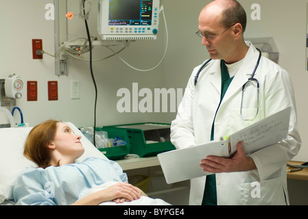 Médecin passe plus de graphique avec patient in hospital Banque D'Images