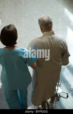 Nurse helping patient walk down hospital corridor Banque D'Images