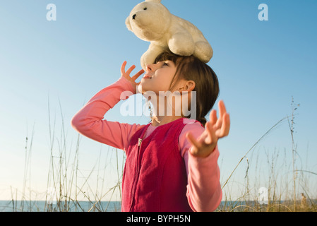 Jeune fille à l'extérieur l'équilibre entre ours polaire en peluche sur la tête Banque D'Images