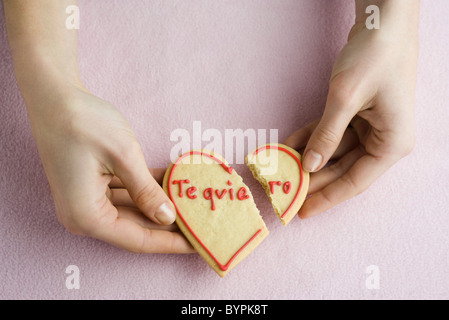 Holding broken heart-shaped cookie Banque D'Images