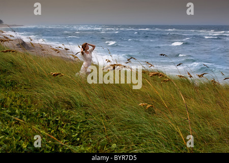 Young woman standing on beach le jour de vent Banque D'Images