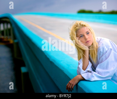 Jeune femme blonde sur bridge daydreaming Banque D'Images