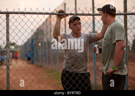 USA, au Mississippi, Gulfport, Jeunes hommes parler au coucher du soleil le long de pit crew fence pendant les courses de stock-car au sud du Mississippi Speedway Banque D'Images