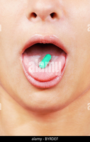 Capsule verte sur un young caucasian woman's tongue close up , vertical Banque D'Images