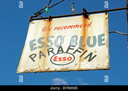 Signe ancien ou vintage suspendu à l'extérieur du magasin disant que nous recommandons Esso Blue paraffine Banque D'Images